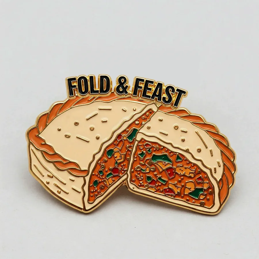 Fold and Feast enamel pin of a folded savoury pastry with gold outlines